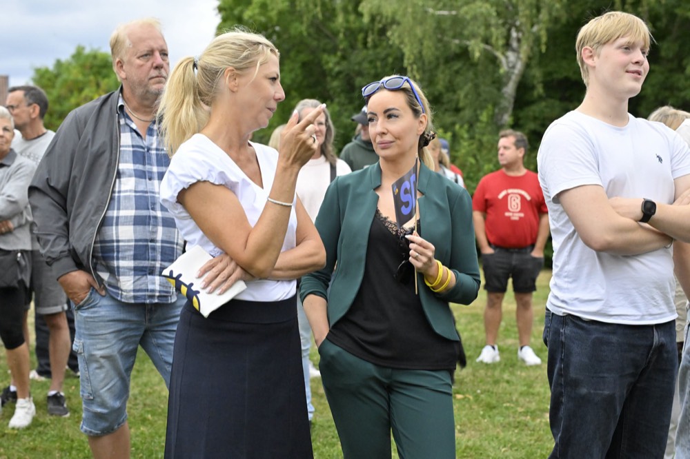 Linda Lindberg i samtal med en besökare under ett kampanjmöte utomhus.
